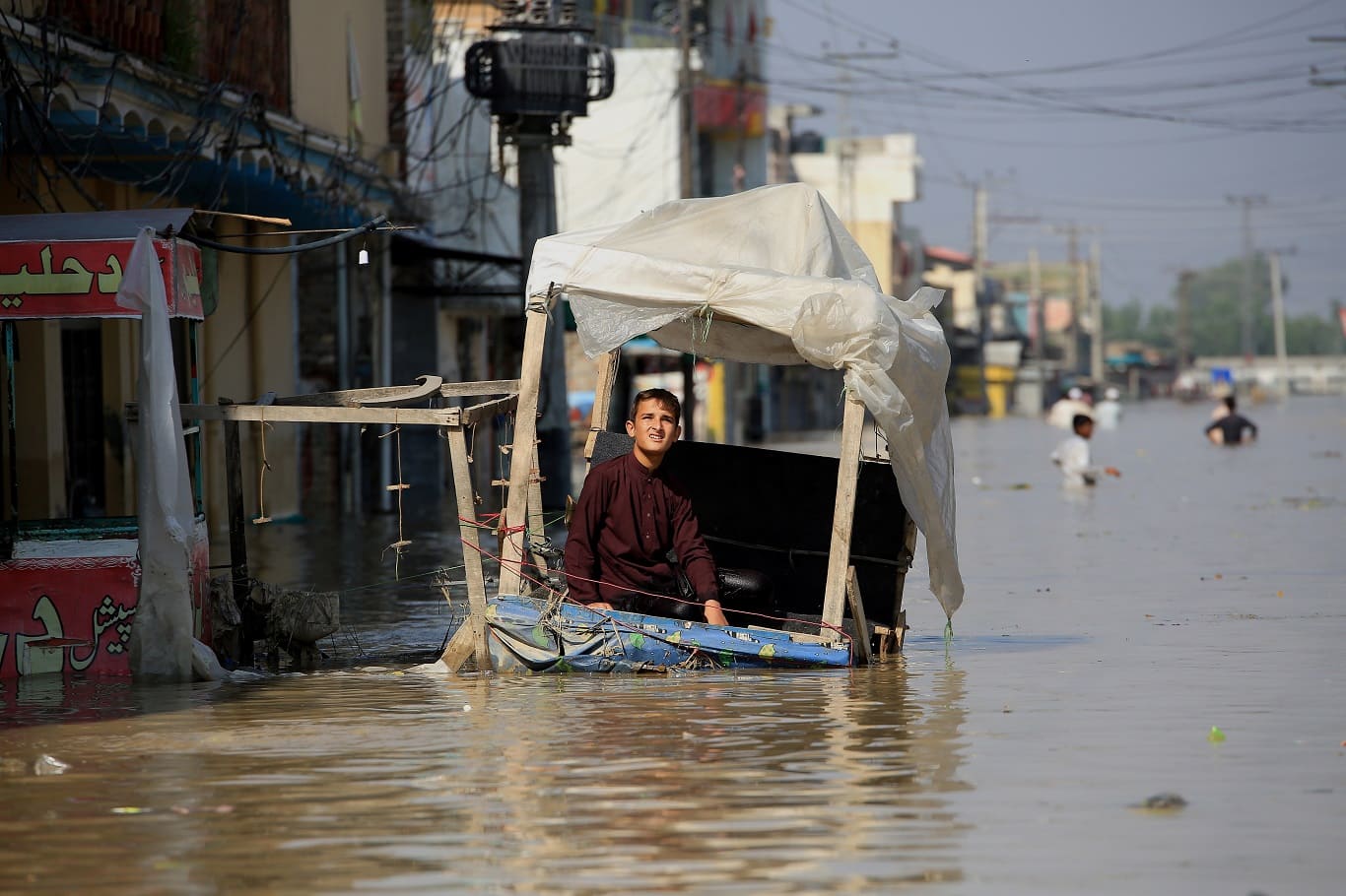 A boy sits on a street stall in a flooded area following heavy rains in Khyber Pakhtunkhwa, Pakistan Photo by Bilawal Arbab/EPA-EFE